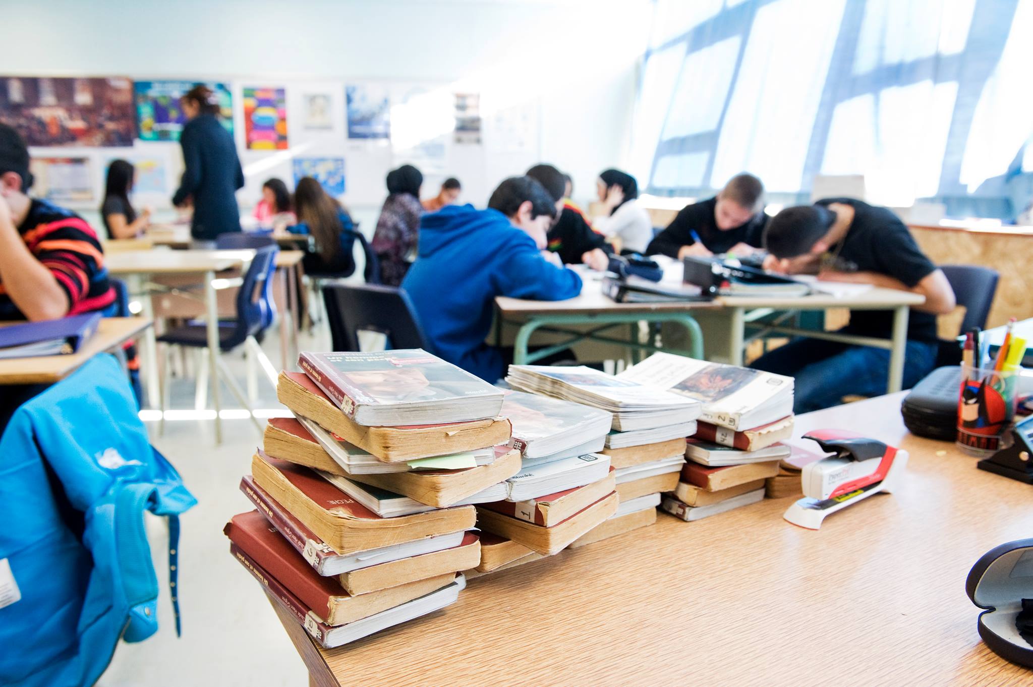 Pile de livres posés sur un bureau, dans une salle de classe.